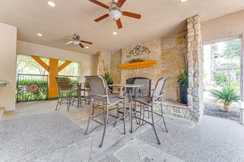A patio with a table and chairs and a ceiling fan.